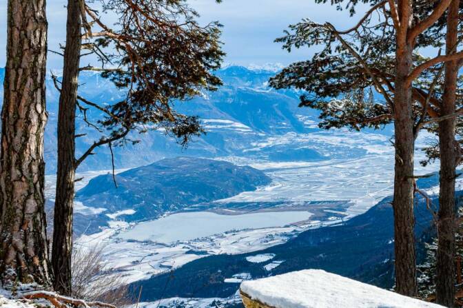 Wandern Südtirol: Schneeschuhwanderung vom Mendel Pass zum Penegal: Ausblick auf das Südtiroler Unterland mit dem Kalterer See und der Leuchtenburg.