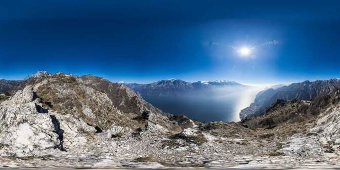 Blick von der Cima Mughera über den Gardasee. Drüben über dem Ostufer des Sees die weißen Gipfel des Monte Altissimo und des Monte Baldo.