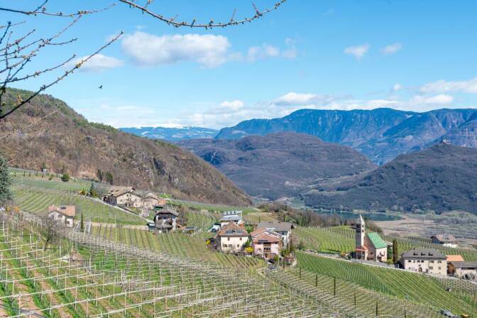 Die Fraktion Söll bei Tramin. Blick auf das Kirchlein zum hl. Mauritius und den Kalterer See im Hintergrund.