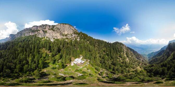 Blick von oben auf die Überetscher Hütte und in die Felswand des Roen
