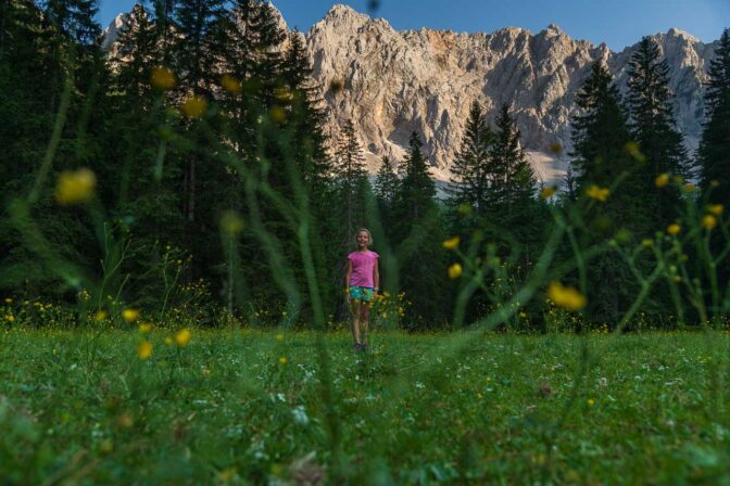 Anna inmitten der zauberhaften Märchenwiese vor der mächtigen Felswand der Karawanken.