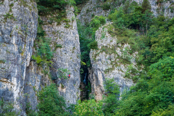 Ein Kletterer in der Ferrata Val del Rio; darüber sieht man Seilbrücken.