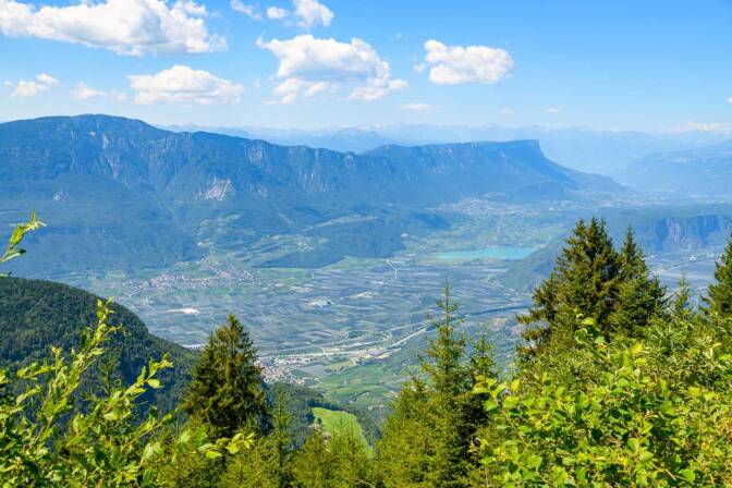 Das Südtiroler Unterland, mit Tramin und dem Kalterer See, bis hinauf nach Kaltern und dem Überetsch. Im Hintergrund: das Mendelgebirge.